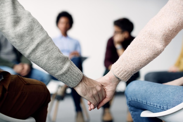 Free photo closeup of two people holding hands during group therapy