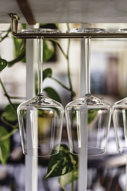 Free photo closeup vertical shot of wine glasses hanging on a rack