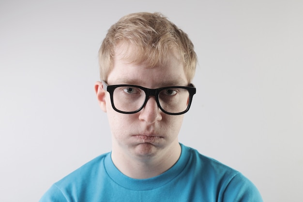 Closeup view of a caucasian male wearing a blue t-shirt and eyeglasses making funny face gestures