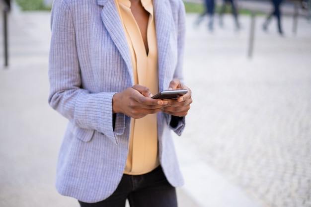 Closeup view of female hands using modern phone on street