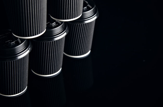 Free photo closeup view on unlabeled set of black take away cardboard paper cups closed with caps in pyramid shape presented on side