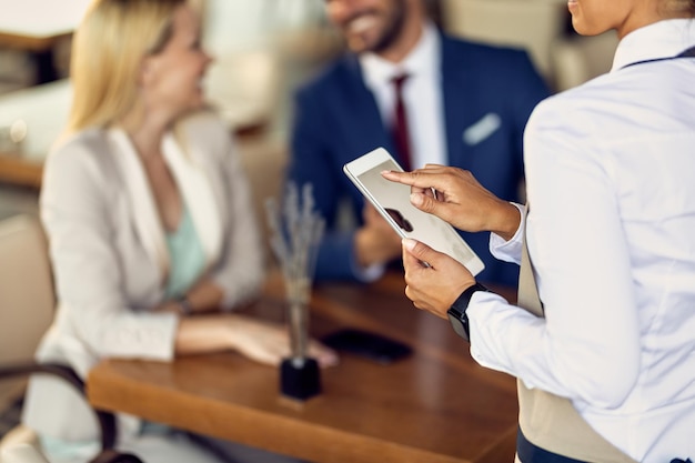 Closeup of waitress using touchpad while taking order in a cafe