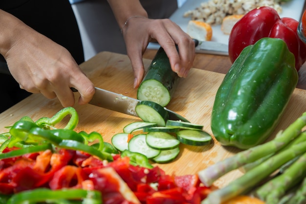 Closeup of woman cutting fresh cucumber