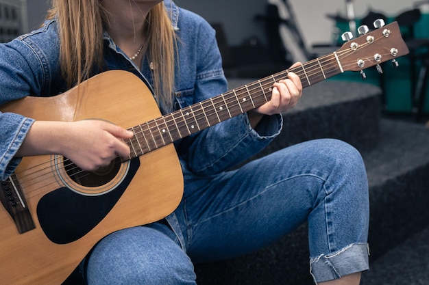 Closeup a woman in a denim suit plays the guitar