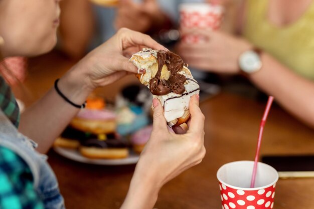 Closeup of woman eating glazed chocolate donut