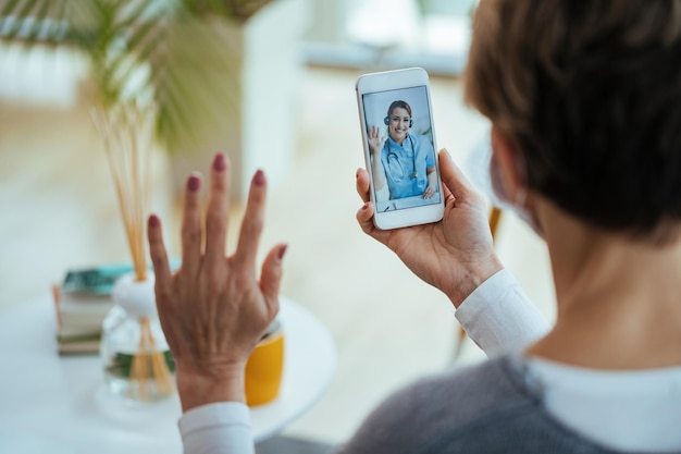 Free Photo closeup of woman greeting her doctor while using smart phone and having video call focus is on female doctor on touchscreen