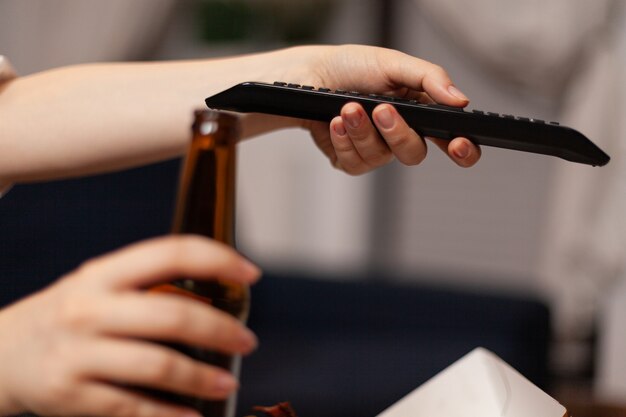 Closeup of woman hands changing channels using remote watching entertainment comedy movie