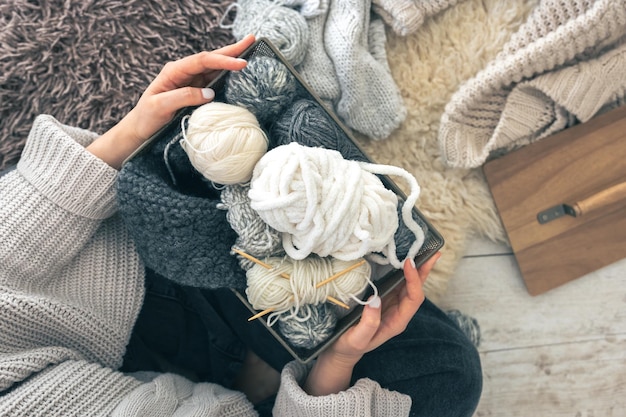 Free photo closeup woman hands wearing in a wool sweater holding box with balls of thread