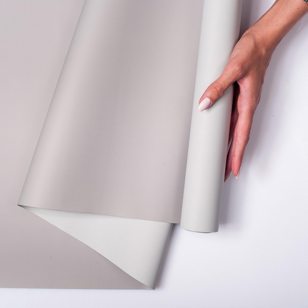 Free photo closeup of a woman holding a roll of gray wallpaper against a white background