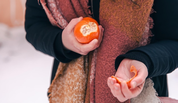 Closeup a woman peels a tangerine blurred background