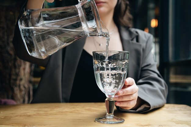 Closeup a woman pours water into a glass in a cafe