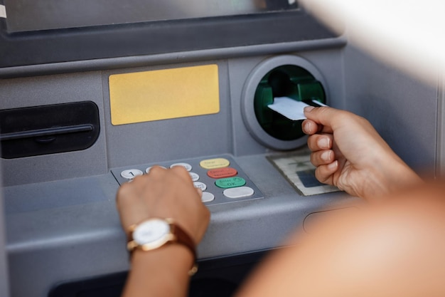 Closeup of woman typing pin code while withdrawing money from ATM