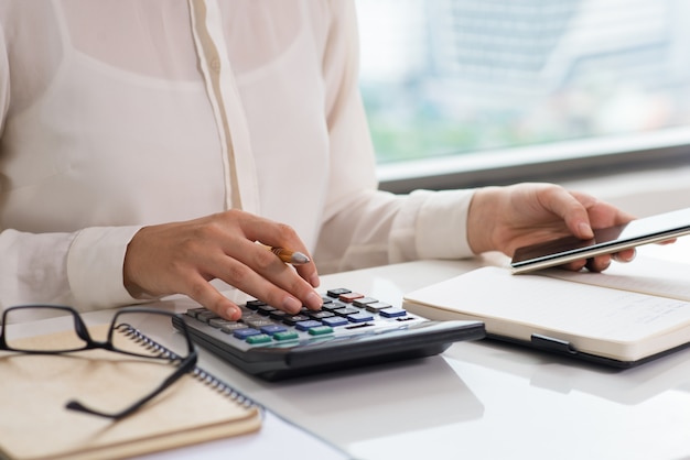 Free photo closeup of woman using calculator and smart phone