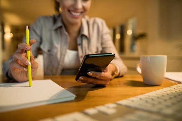 Closeup of woman using smart phone while learning in the evening at home