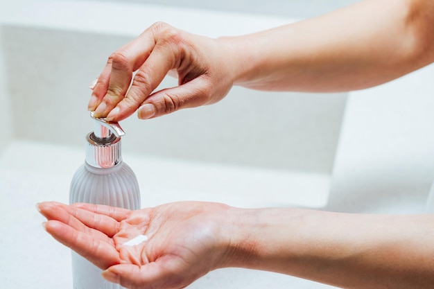 Free photo closeup of woman using soap dispenser while washing hands in the bathroom