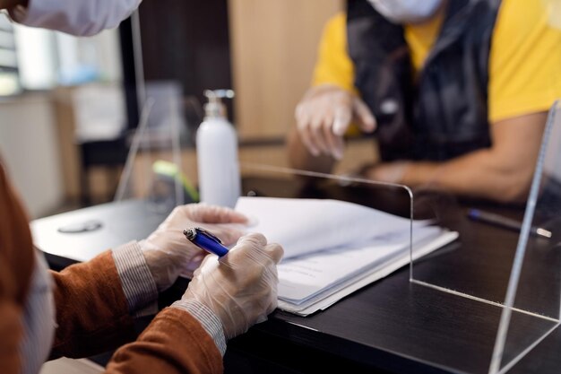 Closeup of woman wearing protective gloves while signing document's at car workshop's office