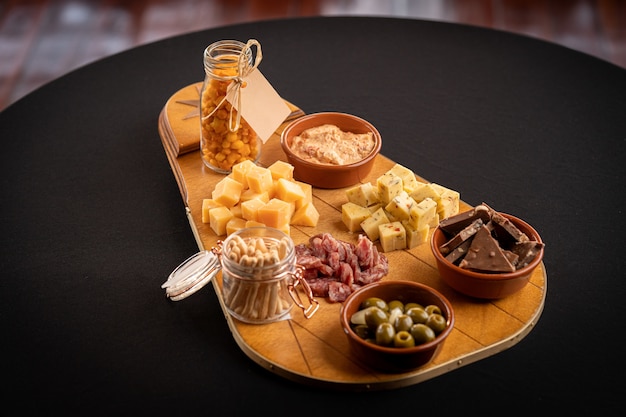 Free photo closeup of a wooden trace with cheese assortment, green olives, chocolate bars