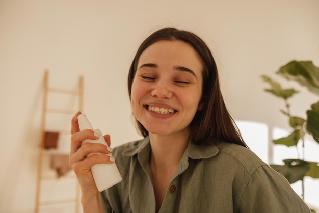 Free Photo closeup of young caucasian brunette woman holding cosmetic milk in light room girl closes her eyes and enjoys facial treatment wellness and self care concept