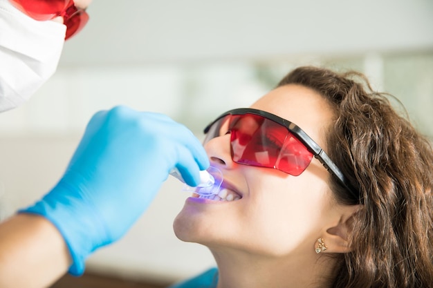 Free photo closeup of young woman having her teeth whitened with ultraviolet light in a dental clinic