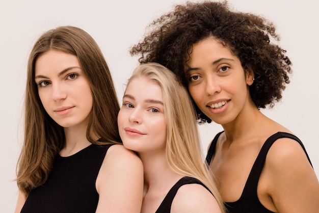 Free photo closeup of young women of different nationalities in black tops looking at camera on white background