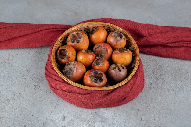 Free Photo cloth-wrapped basket of kakis with seeds removed on marble surface