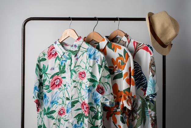 Free Photo clothing rack with hawaiian shirts with floral print on hangers and hat