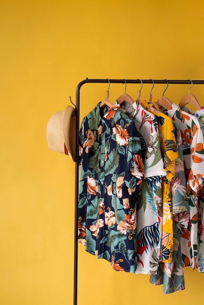 Clothing rack with hawaiian shirts with floral print on hangers and hat