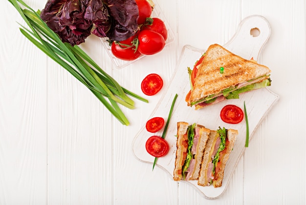 Club sandwich - panini with ham, cheese, tomato and herbs. Top view