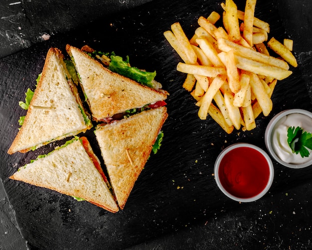 Club sandwiches with tomato ketchup,mayonnaise and potatoes.