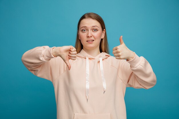 Clueless young blonde woman showing thumb up and down 