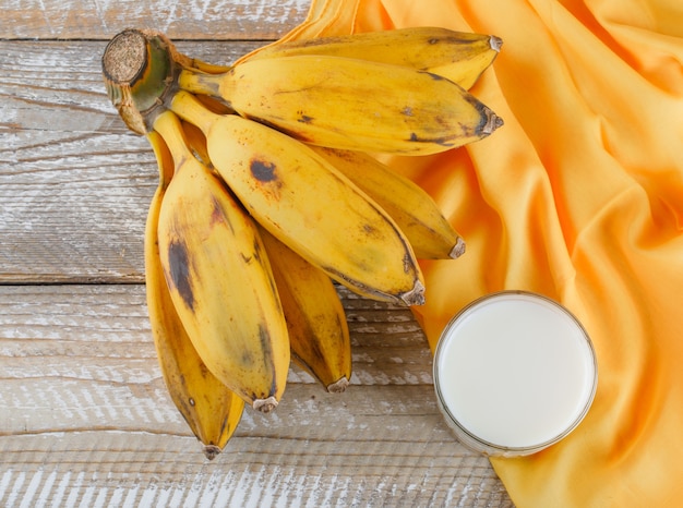 Cluster of bananas with milk on wooden and textile,