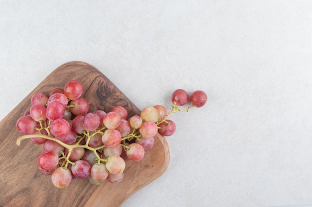 Cluster of fresh grapes on wooden board.