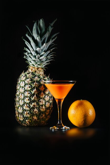 Cocktail and exotic fruits on black background