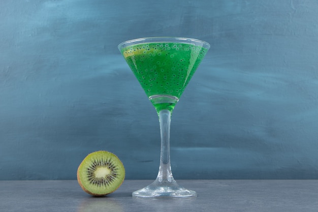 A cocktail glass cup of kiwi juice with a slice of fruit. 