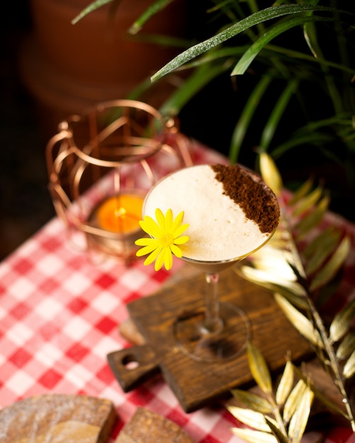 Cocktail with foam and cocoa powder decorated with flower