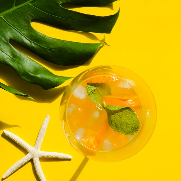 Free photo cocktail with orange, mint and ice near sea star