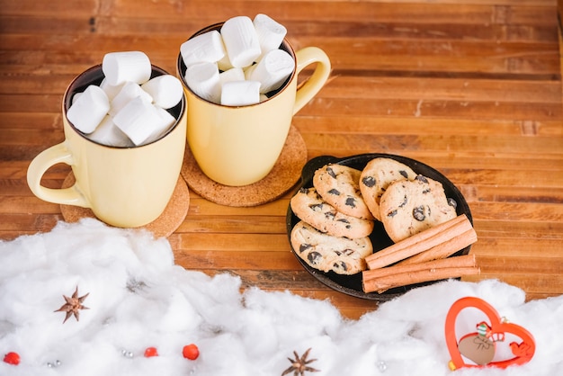 Free photo cocoa cups with marshmallows and plate with cookies