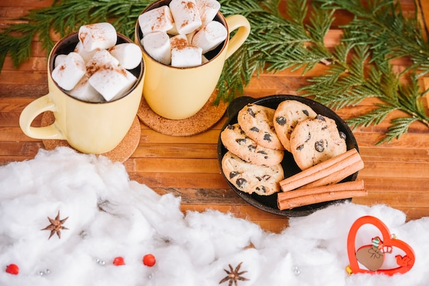 Cocoa mugs and cookies plate near Christmas decorations