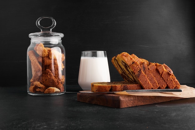 Cocoa pie slices on a wooden board with a glass of milk and dry fruits. 