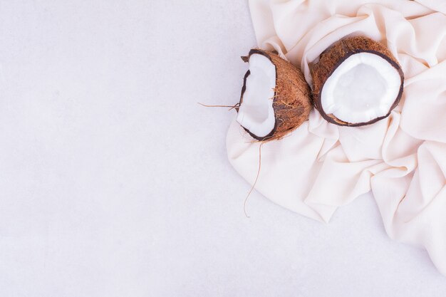 Coconut broken into two pieces on beige tablecloth