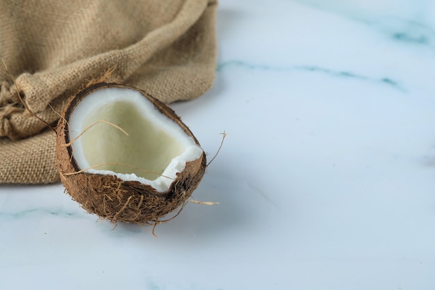 Free Photo coconut fruit on a blue marble with burlap