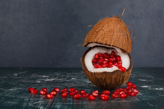 Coconut full of pomegranate on marble surface