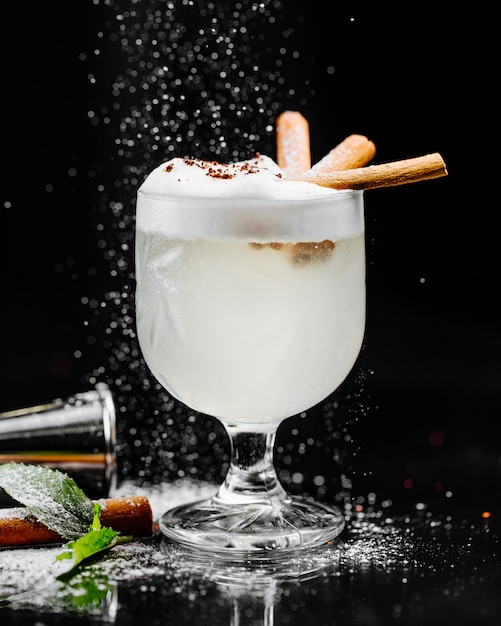 Coconut milky cocktail with foam and cinnamon sticks.