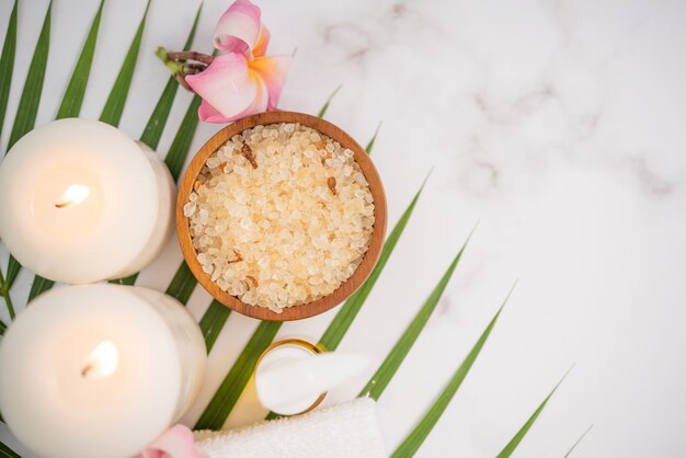 Coconut oil, tropical leaves and fresh coconuts. Spa coconut products on light wooden surface.