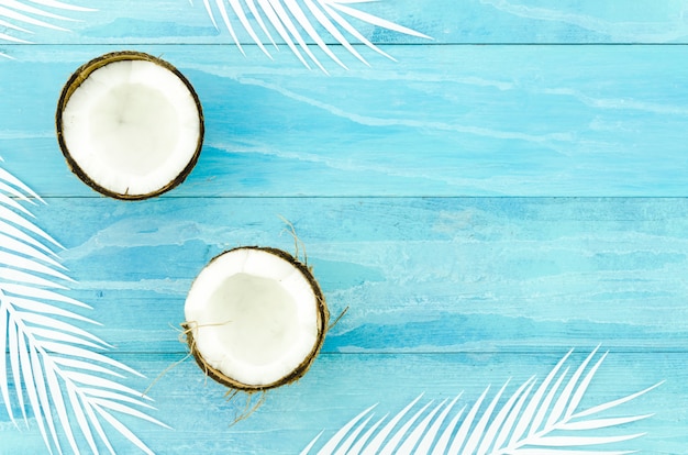 Free photo coconuts with palm leaves on wooden table