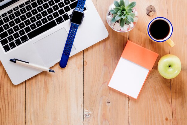 Coffee and apple near stationery and laptop