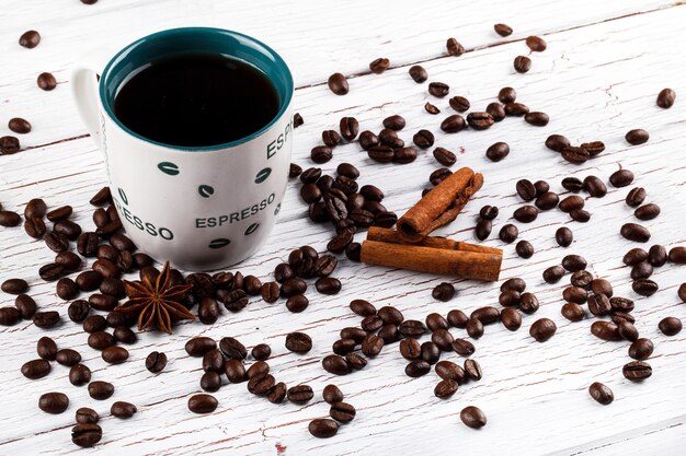 Coffee beans, cinnamon and anise-tree lie before cup of coffee