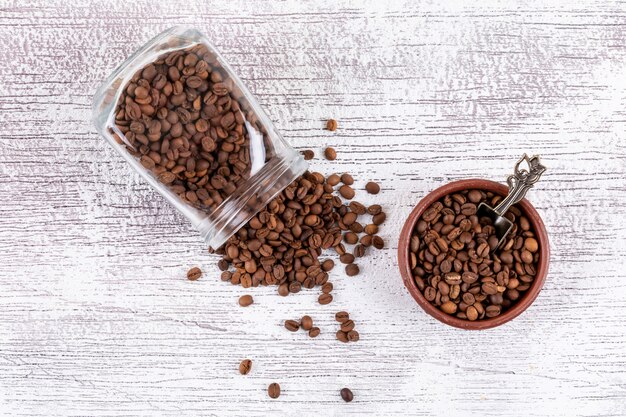 Coffee beans in glass jar and plate on white table