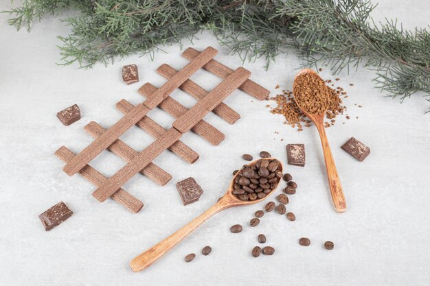 Coffee beans, ground coffee, biscuits and chocolate on marble surface