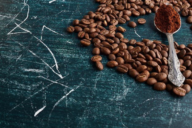 Coffee beans and powder in a metallic spoon. 